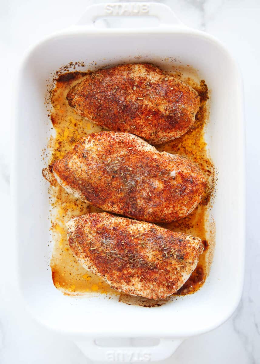 Baked chicken breasts in a white baking dish.