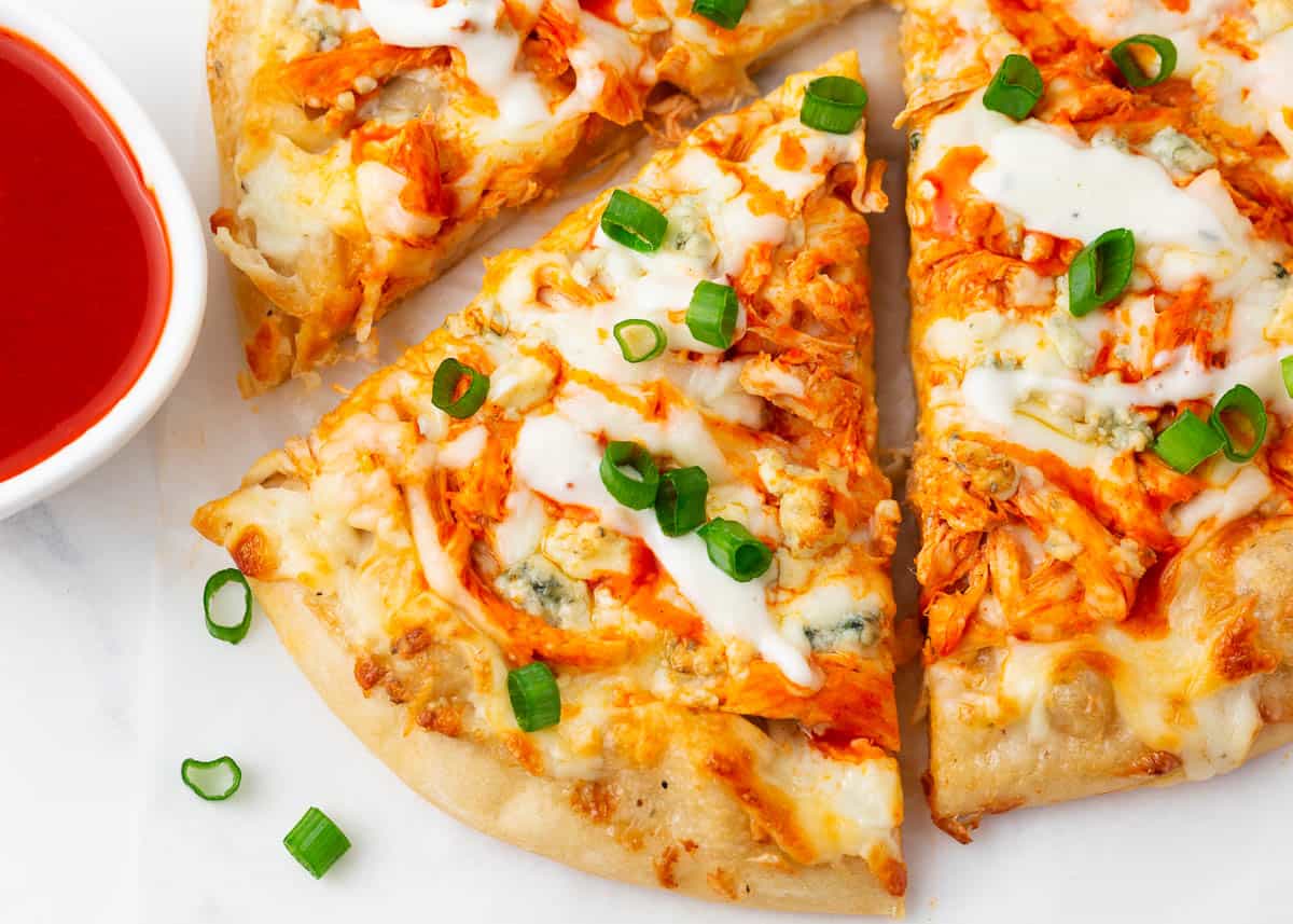 Slice of buffalo chicken pizza with sauce.