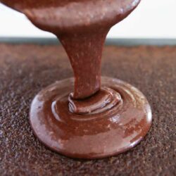 Cooked chocolate icing being poured on top of cake.
