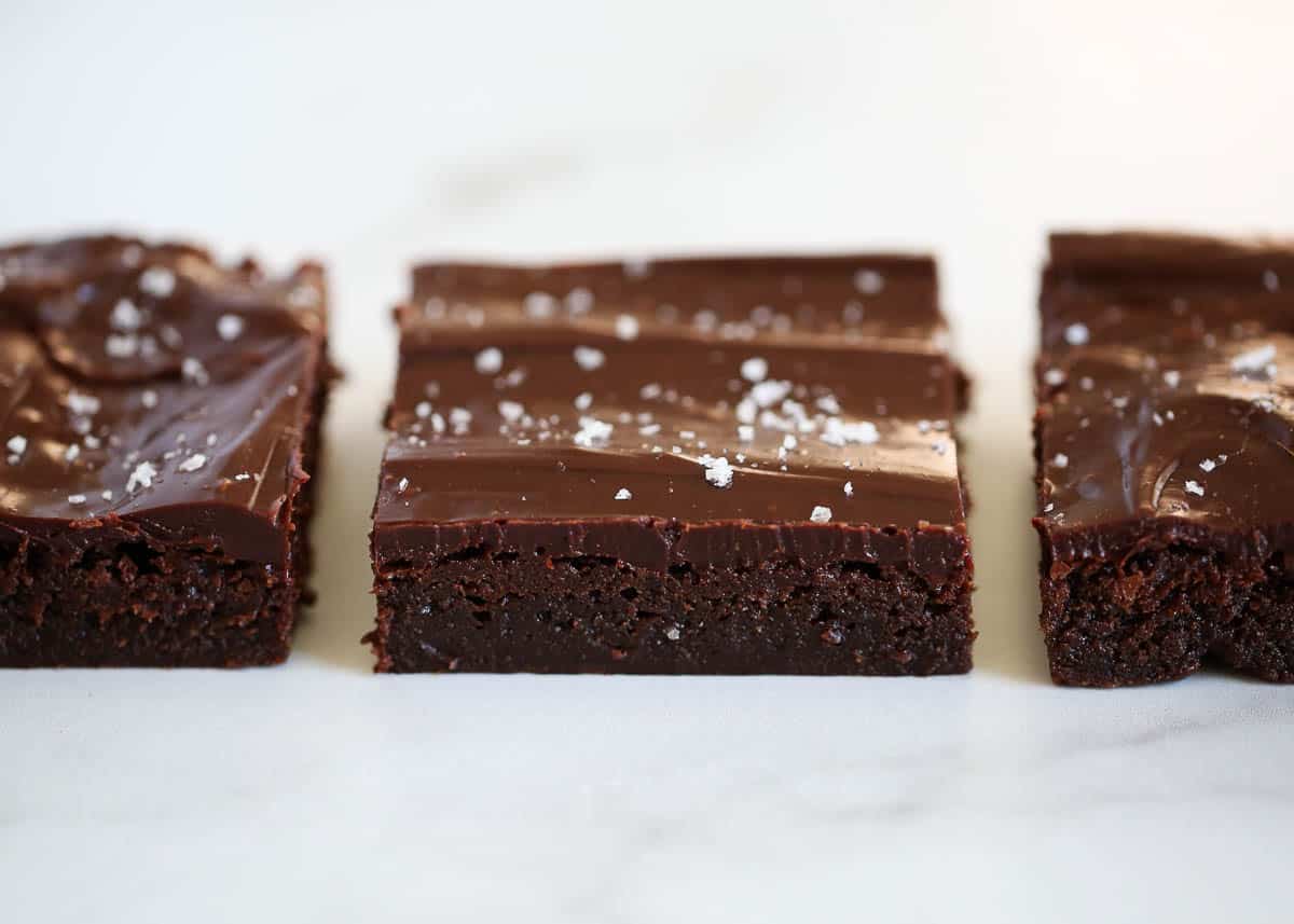 The ultimate rich and decadent fudge frosted brownies that are topped with a smooth, luscious chocolate ganache. These are any chocolate lover's dream! Brownies in a row.