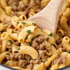 Creamy homemade hamburger helper with ground beef and macaroni stirred in a pot before serving.