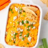 Baked buffalo chicken dip in white baking dish on counter.