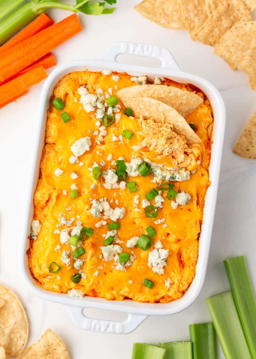Baked buffalo chicken dip in white baking dish on counter.