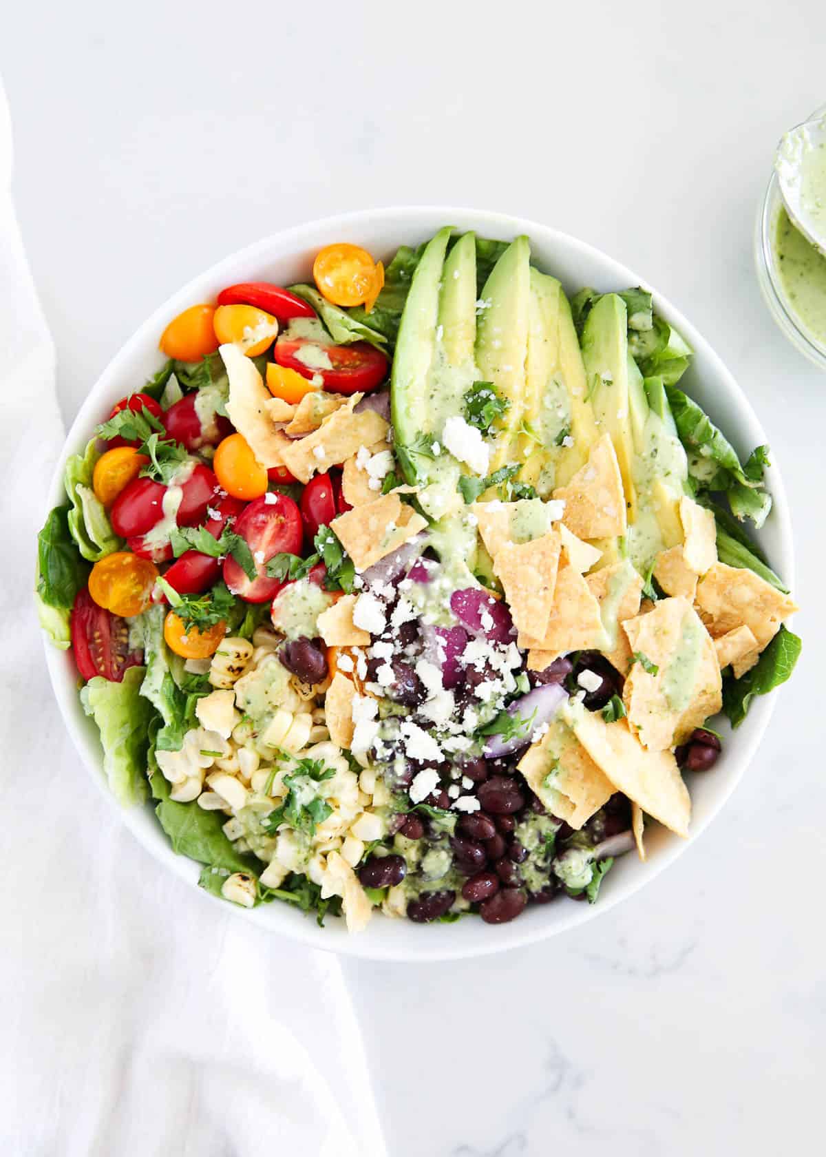 Mexican salad in white bowl on marble countertop.