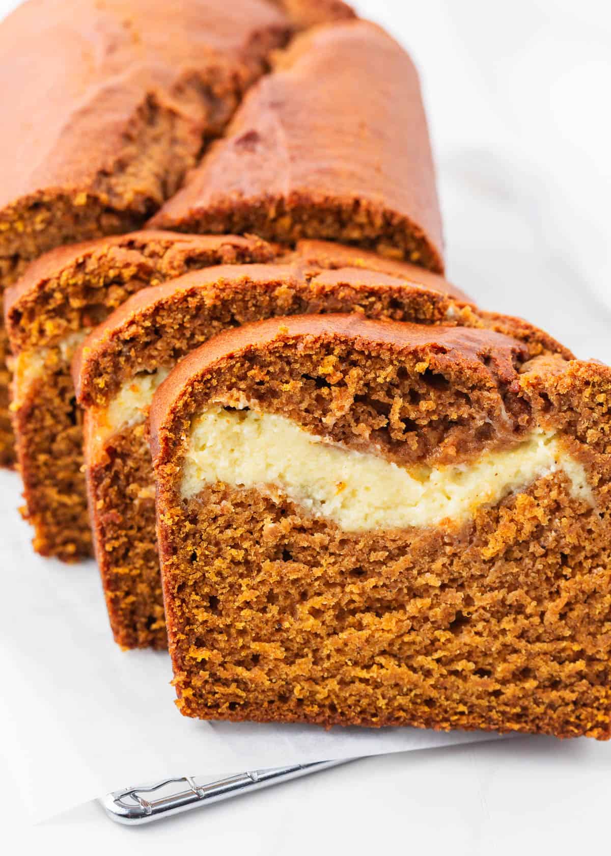 Sliced pumpkin cream cheese bread on parchment paper.