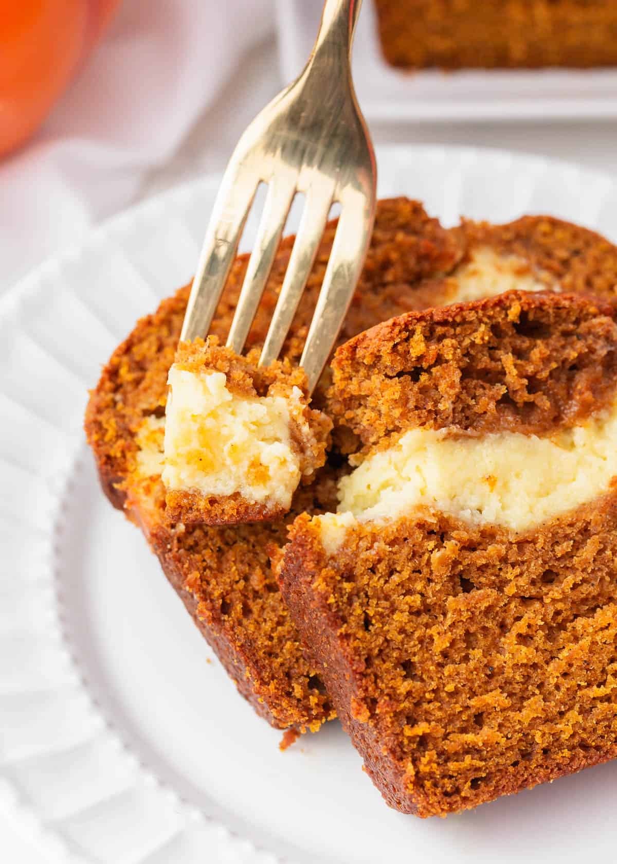 A fork taking a bite of the pumpkin cream cheese bread.