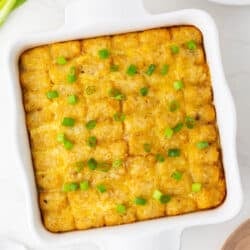 Tater tot breakfast casserole in a white baking dish with green onions.
