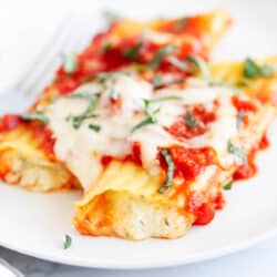 Three cheese manicotti on a white plate.