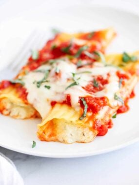 Three cheese manicotti on a white plate.