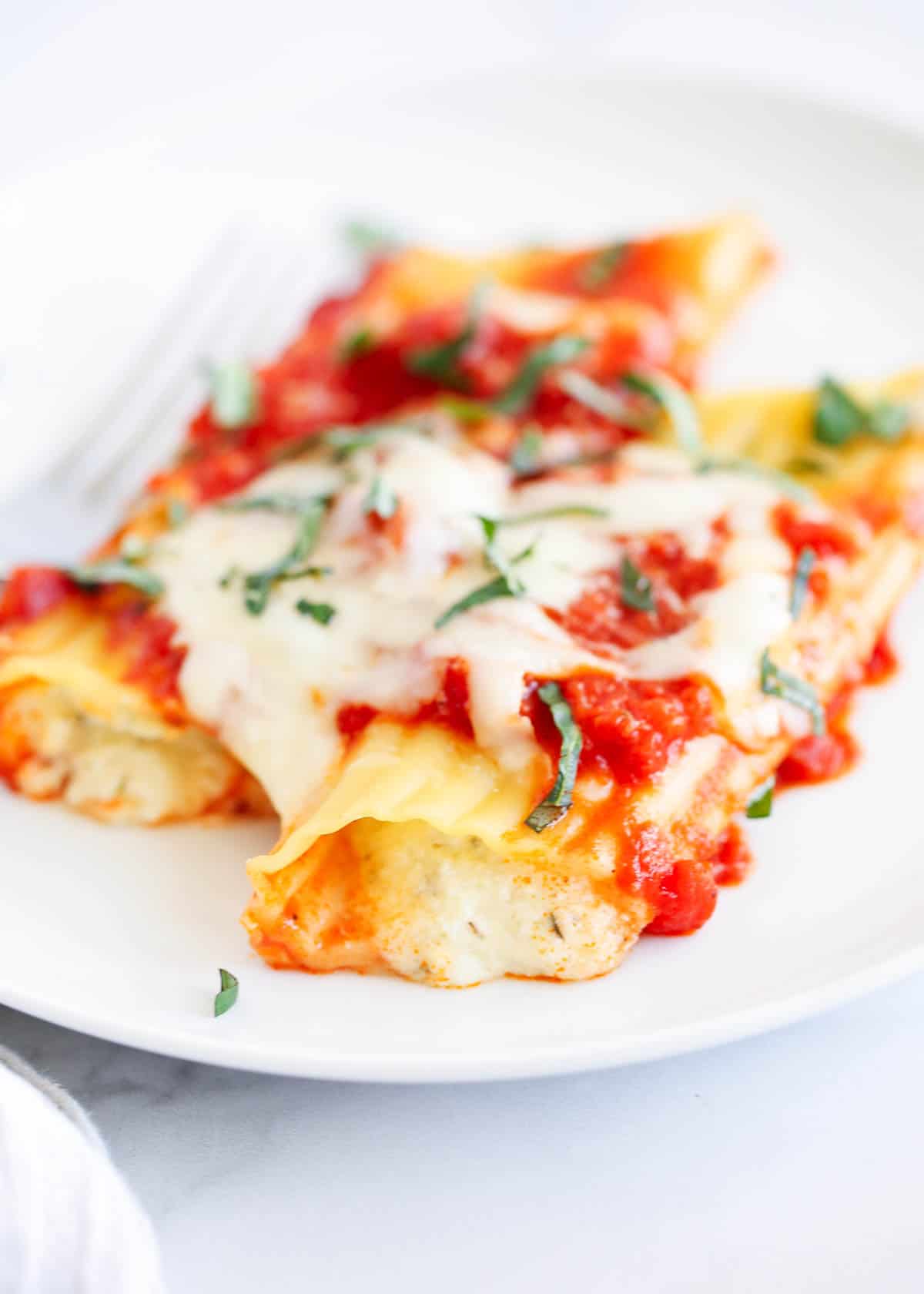 Three cheese manicotti on a white plate.