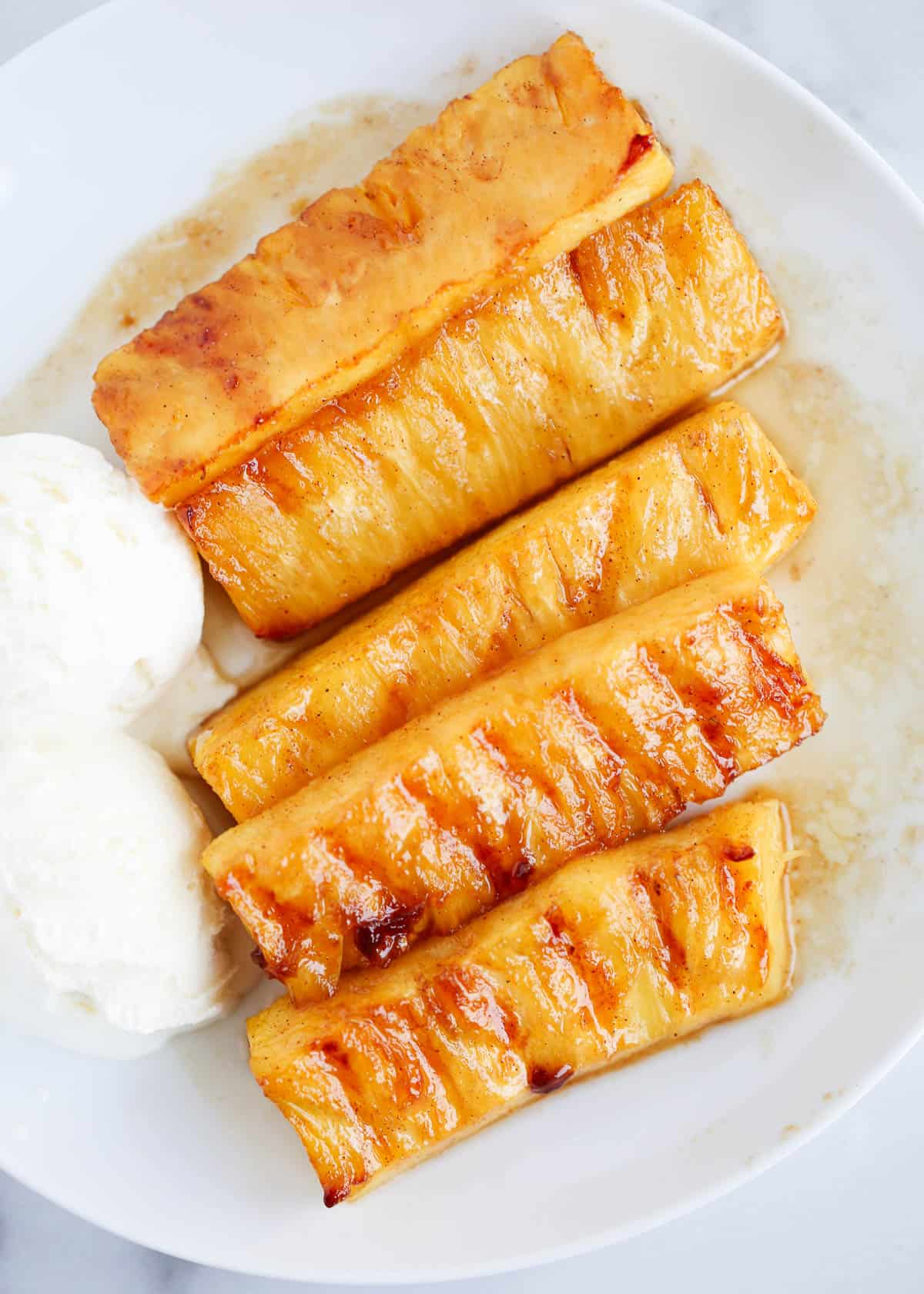 Grilled pineapple on a plate with ice cream.