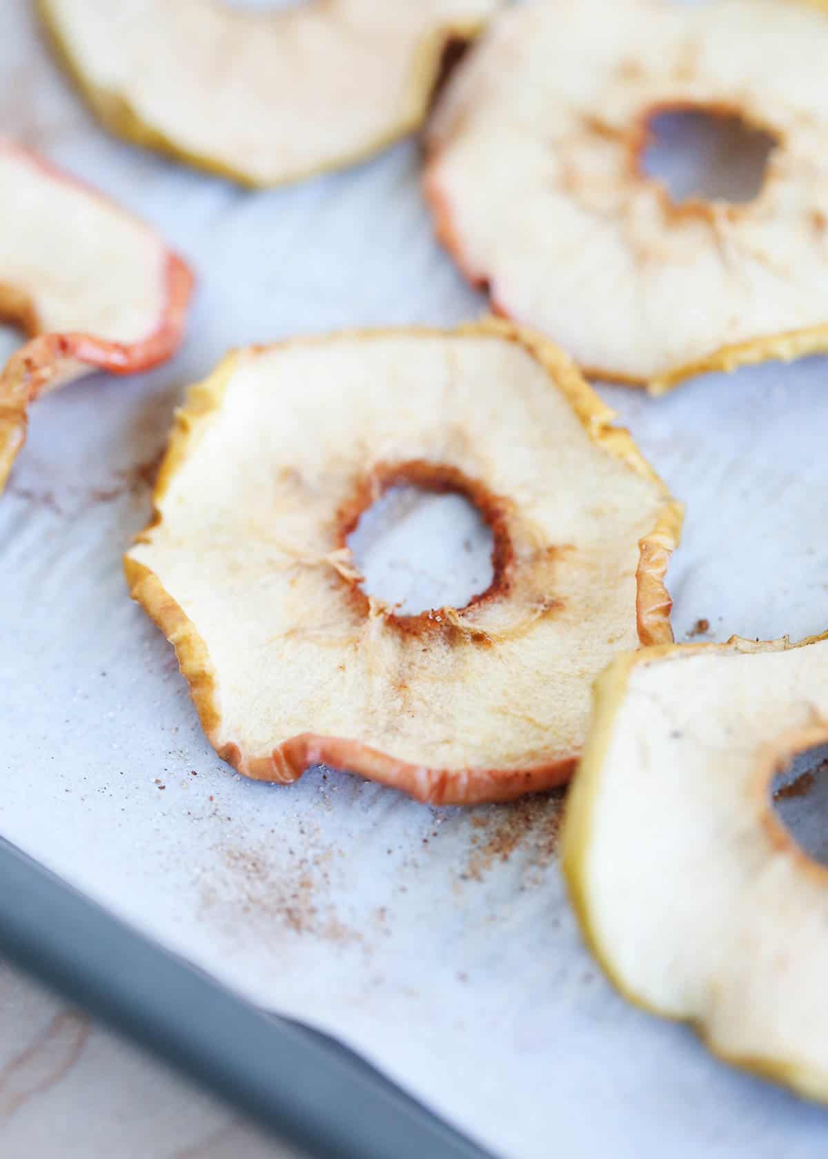 Baked apple chips on a baking sheet.