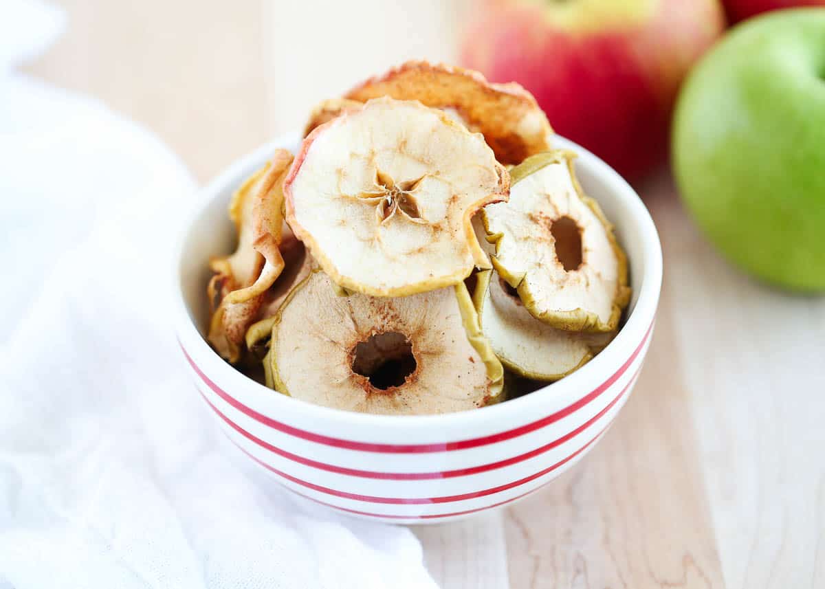 Baked apple chips in a red and white bowl.