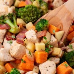 Chicken and apples in a pot with wooden spoon.