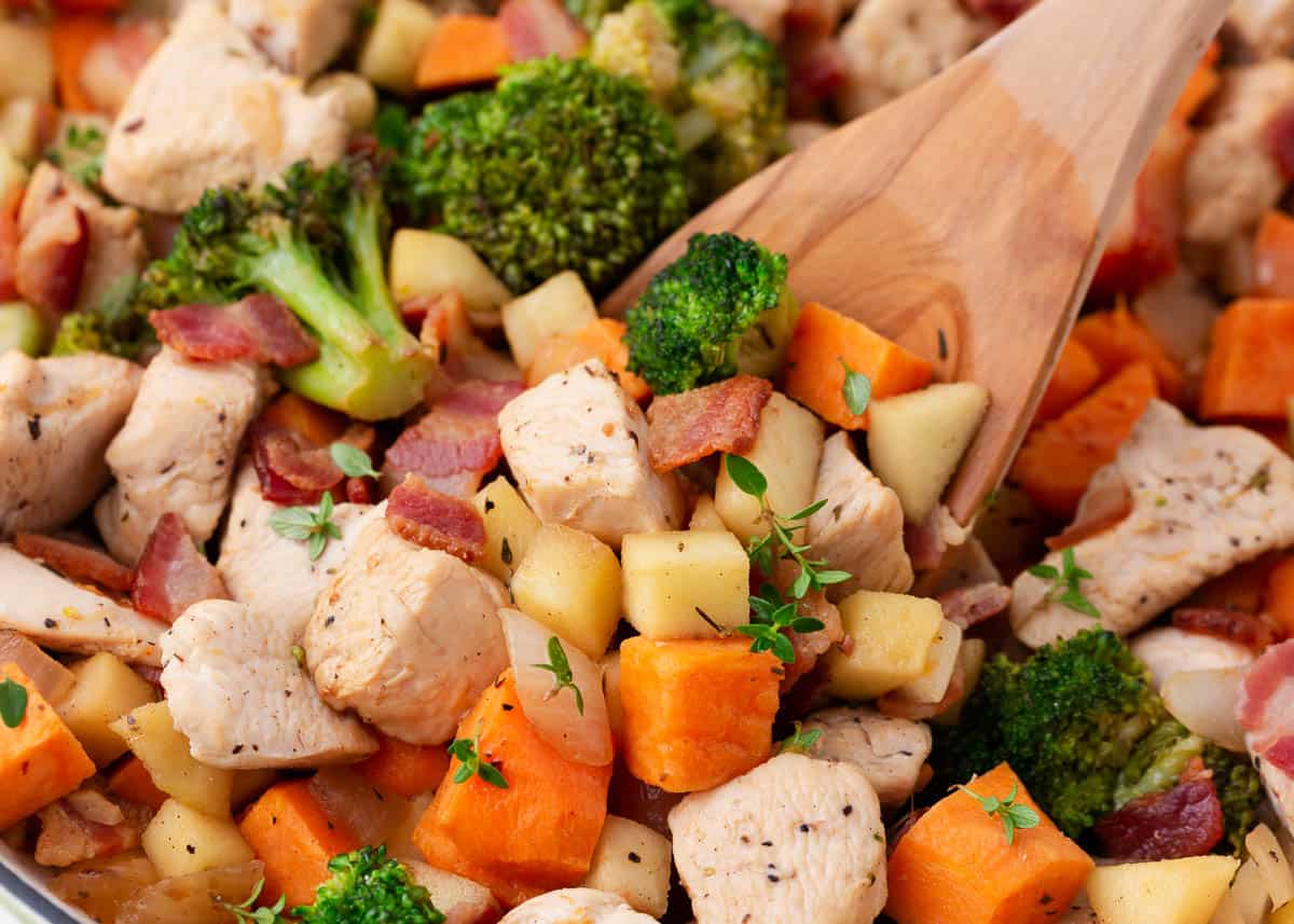This one pan chicken and apples is an easy and rustic dinner option made with healthy vegetables and apples. This dish is the quintessential fall recipe! Chicken and apples in a pot with wooden spoon.