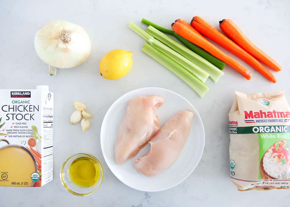 Chicken and rice soup ingredients on marble counter.