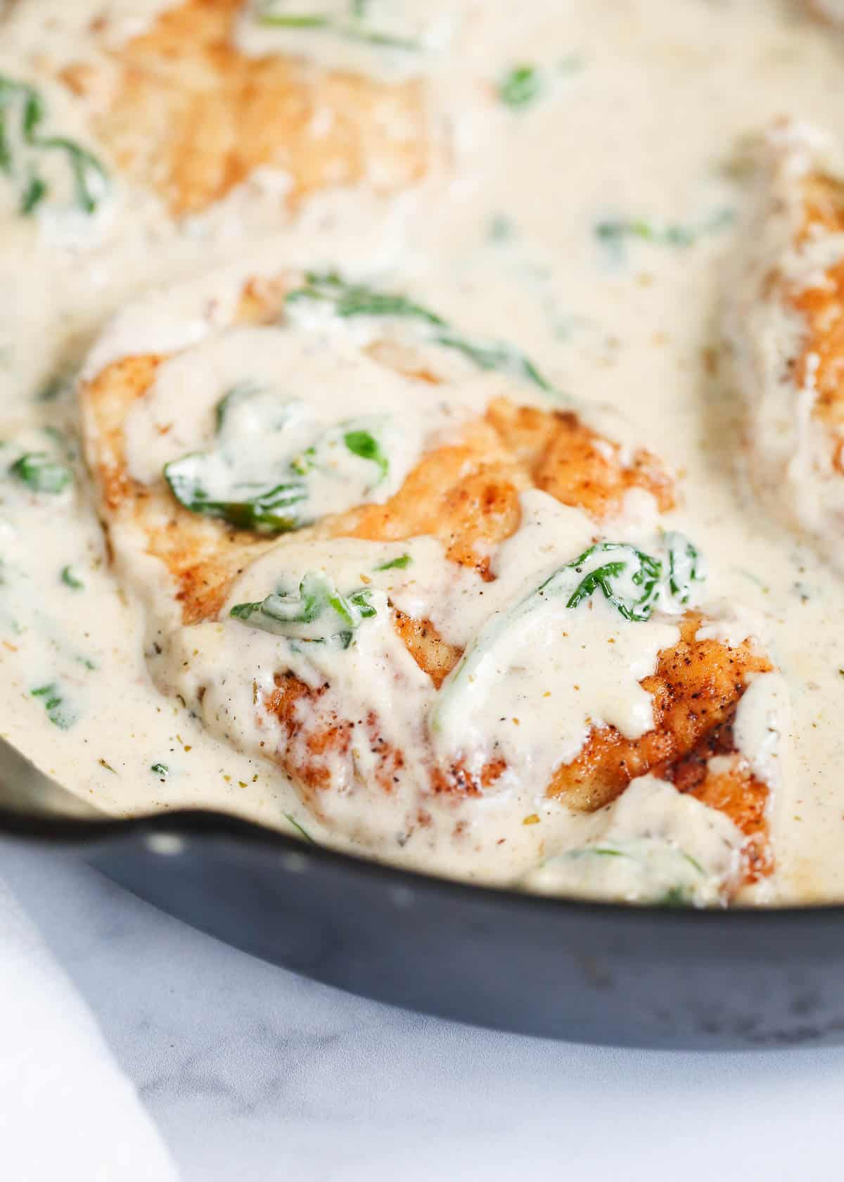 Close up of chicken florentine in a cast iron skillet.