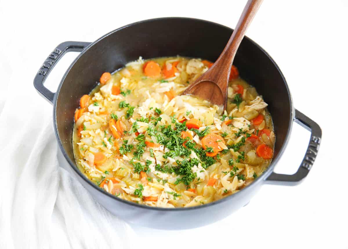 Chicken orzo soup in a black staub pot.