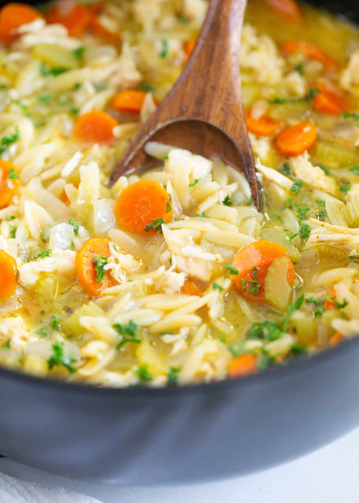 Chicken orzo soup in a black pot.