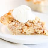 Slice of dutch apple pie on a white plate with ice cream.