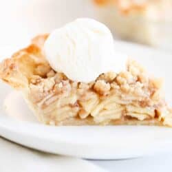 Slice of dutch apple pie on a white plate with ice cream.