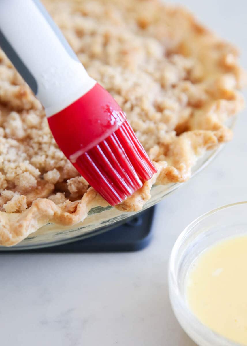 Brushing egg wash onto a pie crust.