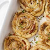 Ham and cheese pinwheels in a white baking dish.