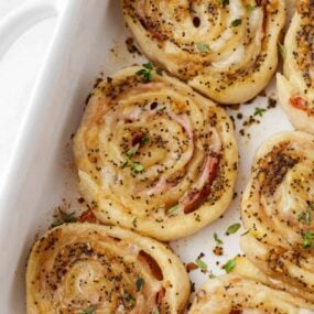 Ham and cheese pinwheels in a white baking dish.