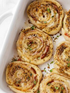 Ham and cheese pinwheels in a white baking dish.