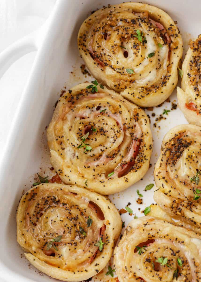 Ham and cheese pinwheels in a white baking dish.