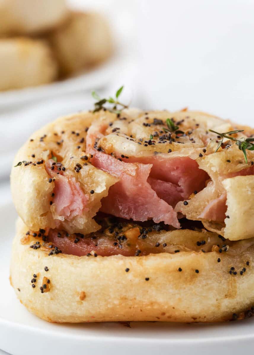 Stacked ham and cheese pinwheels on a white plate.