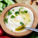 Homemade hummus in a wooden bowl with vegetables.