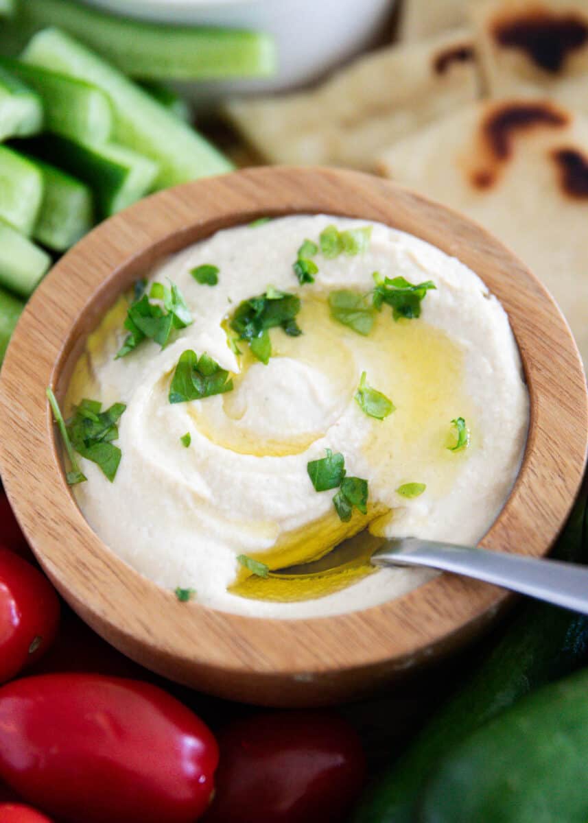 Homemade hummus in a wooden bowl with vegetables. 