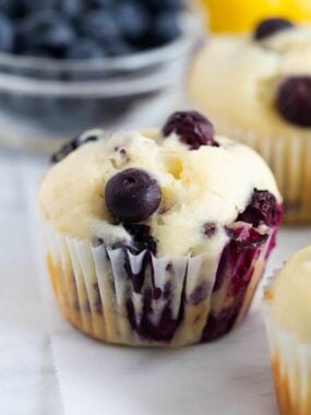 Close up of a lemon blueberry muffin with sour cream on the countertop.