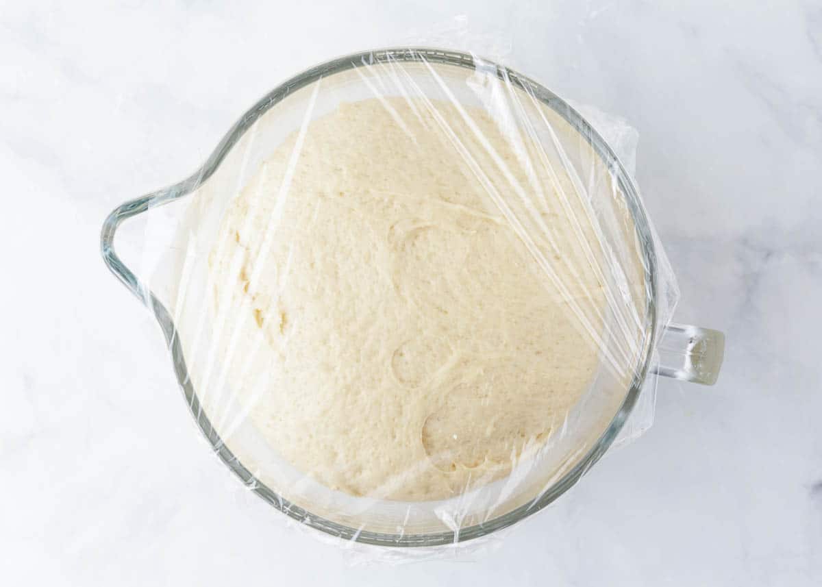 Bread dough rising in a glass bowl.