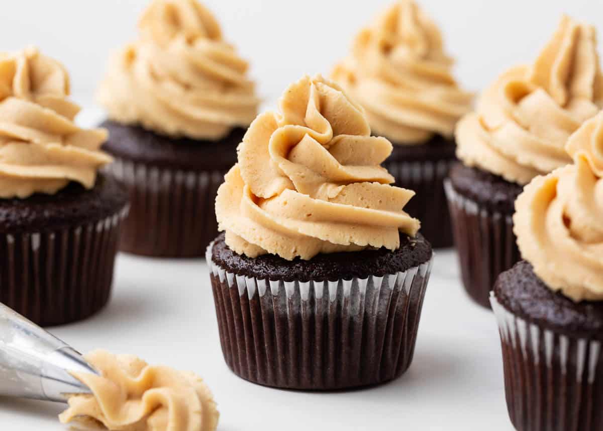 Looking for the perfect addition to your chocolate desserts? How about peanut butter frosting?! Rich buttercream is flavored with creamy peanut butter to create a decadent frosting you can pipe or spread onto all your favorite treats. Peanut butter frosting on top of a chocolate cupcake.