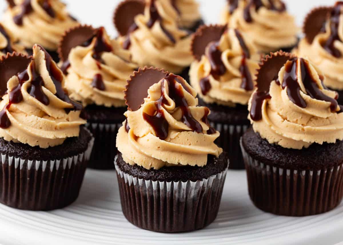 Chocolate peanut butter cupcakes on a cake platter.