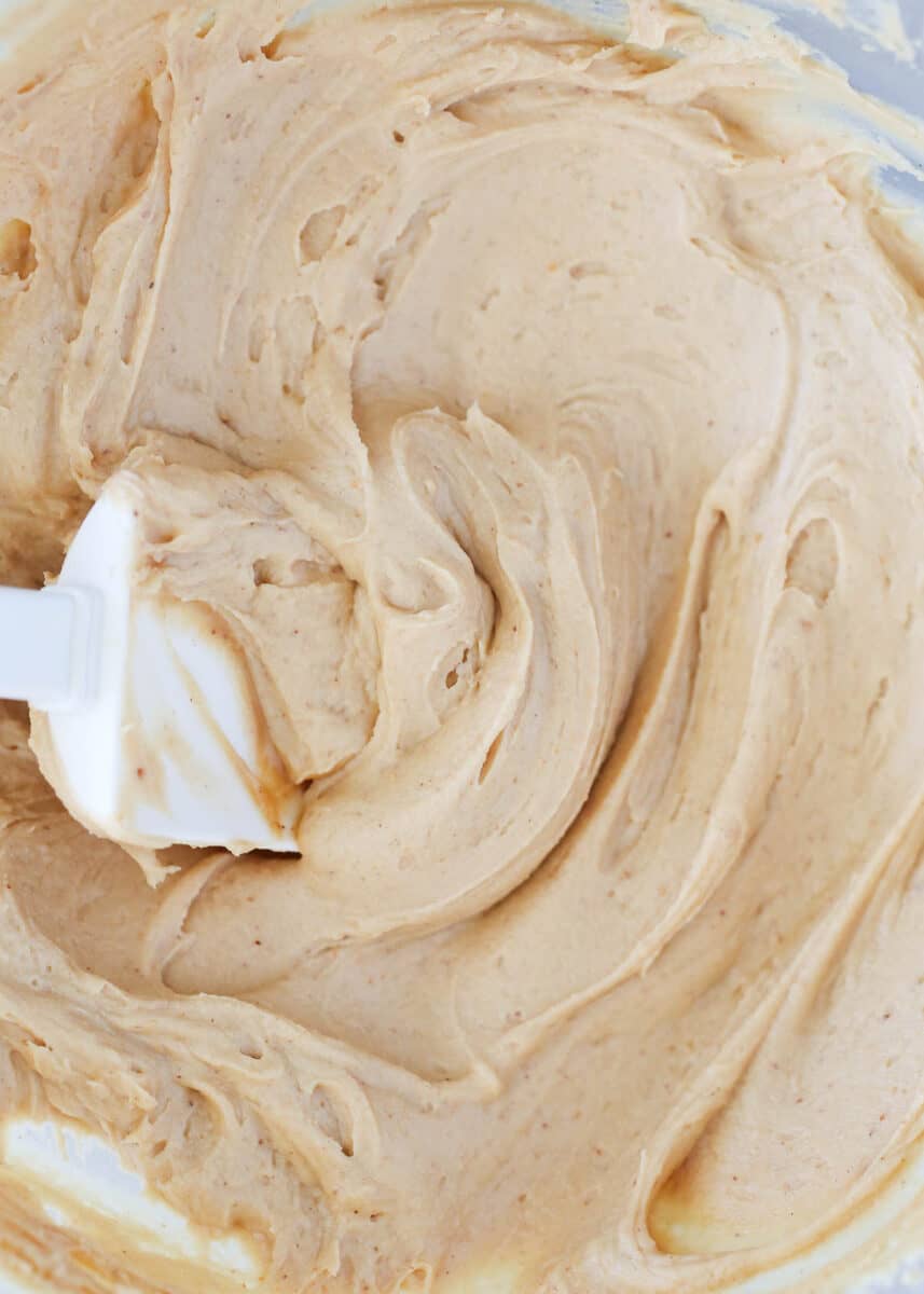 Peanut butter frosting in a glass bowl with spatula.