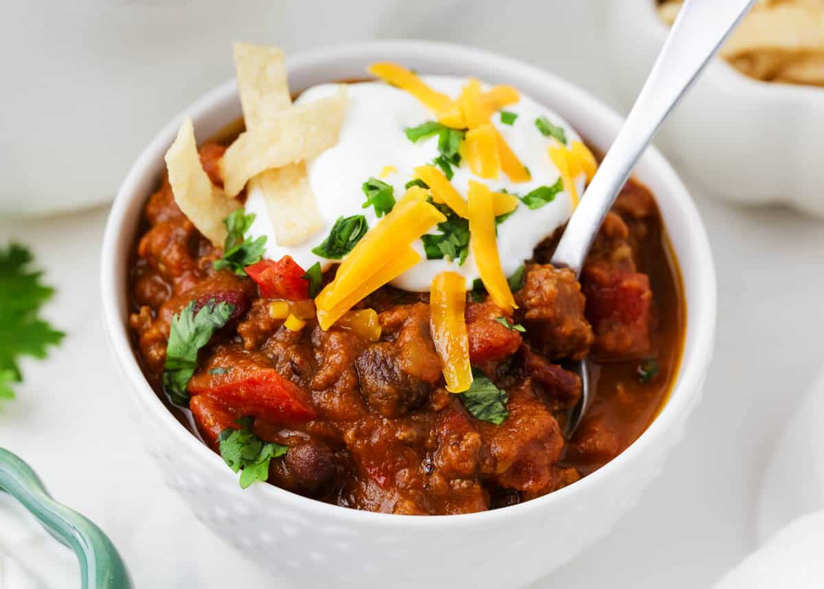 Pumpkin chili in a white bowl with a spoon.