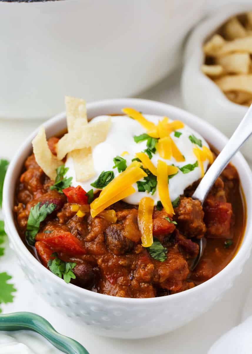 Pumpkin chili in a white bowl with a metal spoon.
