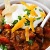 Pumpkin chili in a white bowl with cheese and sour cream on top.