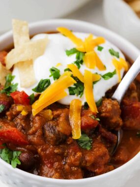 Pumpkin chili in a white bowl with cheese and sour cream on top.