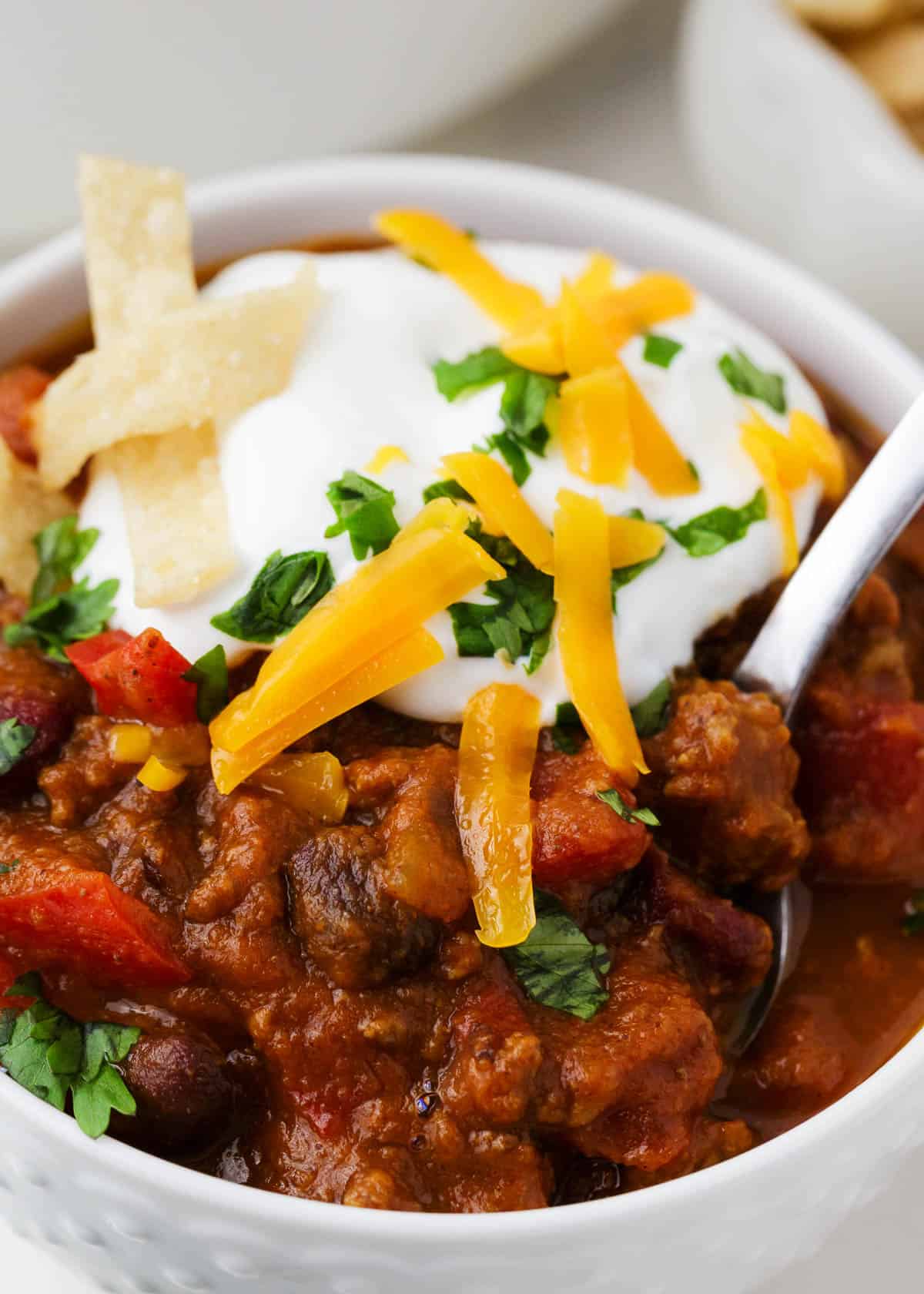 Pumpkin chili in a white bowl with cheese and sour cream on top.