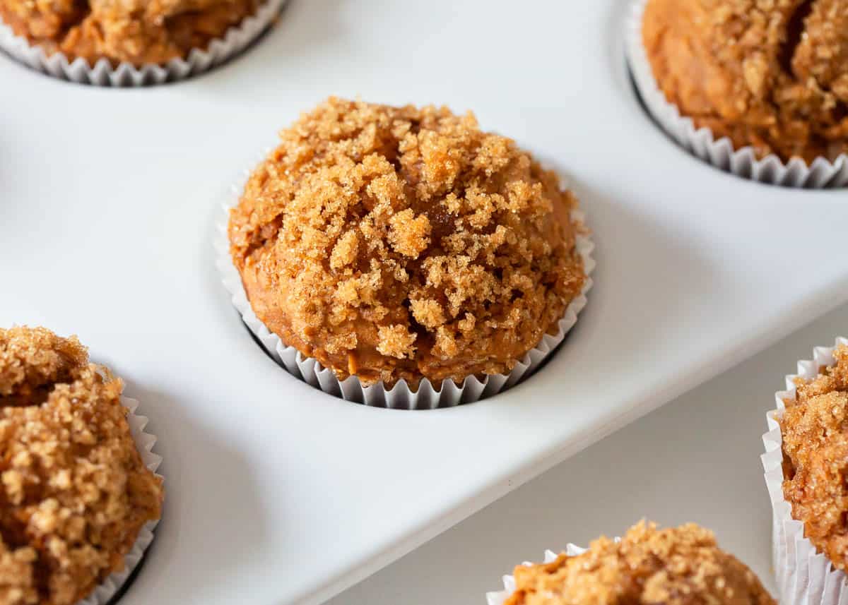 Pumpkin muffins with brown sugar topping on top in a muffin pan.