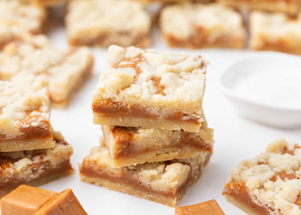 A melt-in-your-mouth butter shortbread filled with an ooey gooey caramel layer is what these salted caramel butter bars are all about. Ready to devour in just over an hour, these buttery caramel bars are everyone's favorite! Caramel butter bars stacked on counter.