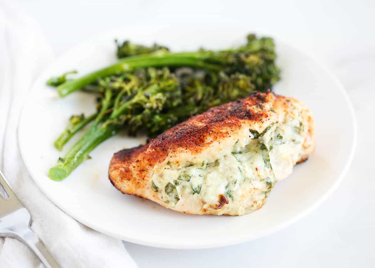 Spinach stuffed chicken breast cooking on a white plate.