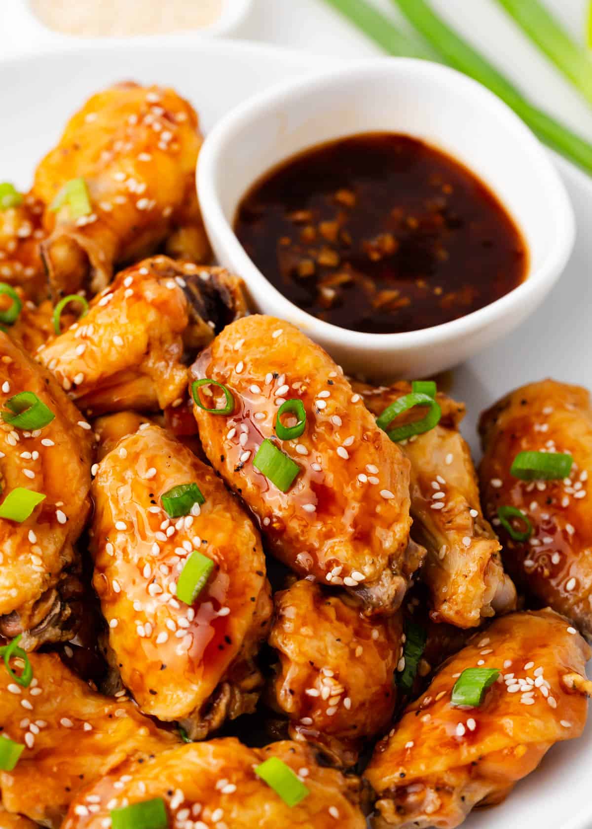 Teriyaki chicken wings on white plate with teriyaki sauce.