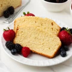 Two slices of classic pound cake on a plate with fresh berries.