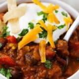 Pumpkin chili in a white bowl with cheese and sour cream on top.