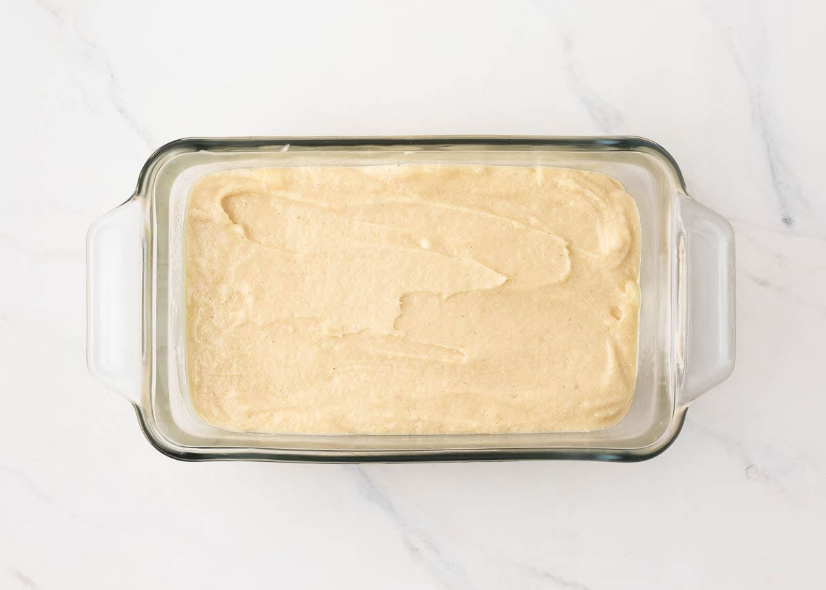 Pound cake batter spread evenly in a glass loaf pan ready to bake.